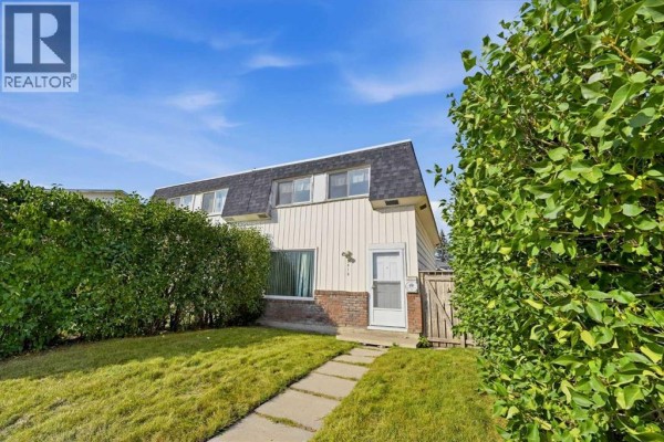Side view of the duplex with a manicured lawn and a paved pathway leading to the door. - 3012 Dover Crescent Se, Calgary