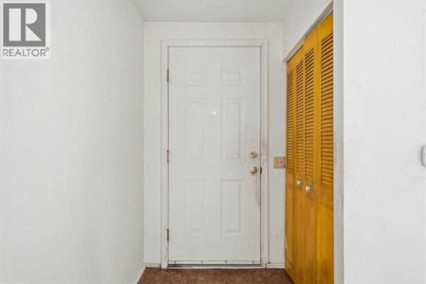 Interior view of a white front door next to a louvered closet in a small entryway. - 3012 Dover Crescent Se, Calgary