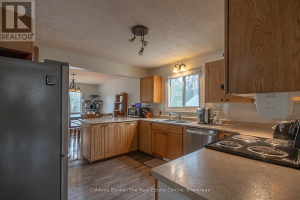 Kitchen with light oak cabinets, stainless steel appliances, a double sink, and a dining area view. - 3016 118 Highway, Bracebridge