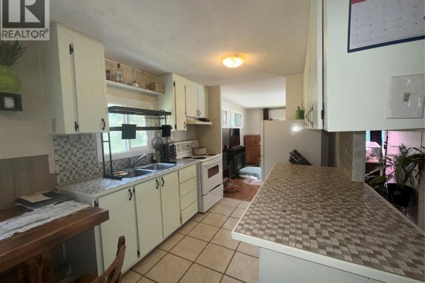 Kitchen with white cabinets, beige tile floor, white appliances, and a mosaic tile backsplash. - 3018 Perrier Road Unit# 14, Nelson