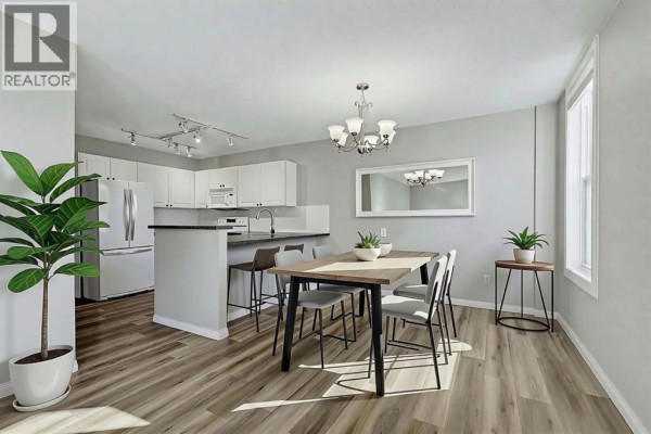 Kitchen with white cabinets, stainless steel appliances, and island with bar stools. - 302, 1328 13 Avenue Sw, Calgary