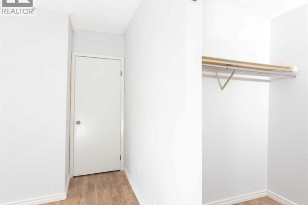 Hallway with a closed door and an open closet with a shelf and hanging rod. - 302, 2611 15a Street Sw, Calgary