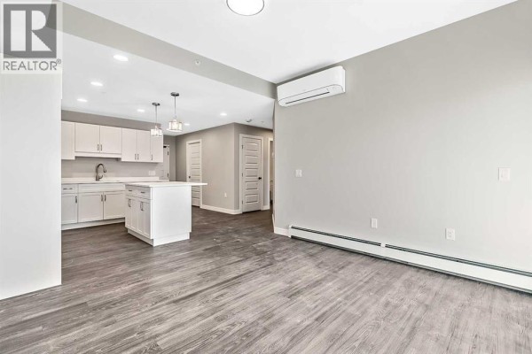 Living area showing open layout with air conditioning unit and access to kitchen. - 302, 97 Station Drive, Sylvan Lake