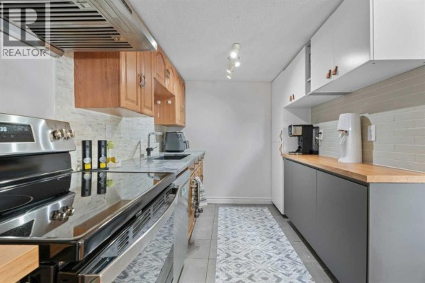 Kitchen counter space with coffee maker, water dispenser, and subway tile backsplash. - 302, 9930 Bonaventure Drive Se, Calgary
