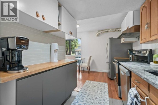 Kitchen with view of dining area, refrigerator, and stainless steel range. - 302, 9930 Bonaventure Drive Se, Calgary