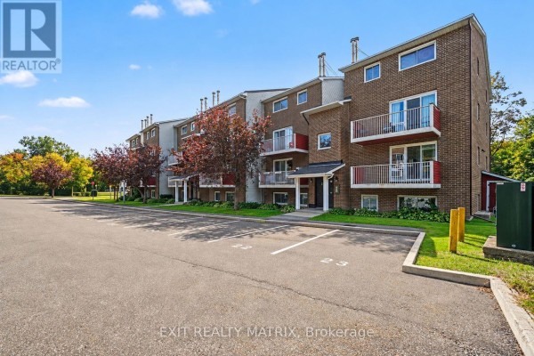 Side view of brick apartment building exterior with parking lot and green lawn. - 302 - 1589 St. Bernard Street, Ottawa