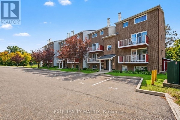 Side view of brick apartment building exterior with parking lot and green lawn. - 302 - 1589 St. Bernard Street, Ottawa
