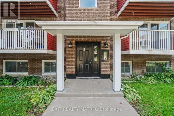Entrance to apartment building with double black doors, porch light, and white pillars. - 302 - 1589 St. Bernard Street, Ottawa