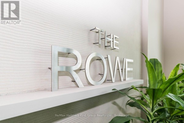 Close-up of metal lettering spelling "THE ROWE" on a textured wall. - 302 - 1600 Charles Street, Whitby