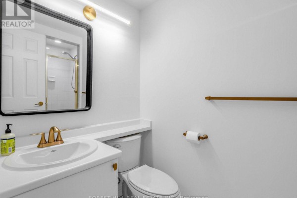 Another view of the white bathroom showcasing the sink, toilet, and a towel rack. - 302 - 1818 Bayview Avenue, Toronto