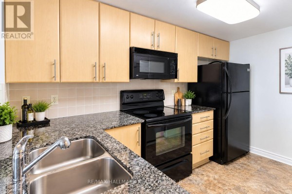 Kitchen with light wood cabinets, black appliances, and granite countertops. - 302 - 200 Lett Street, Ottawa