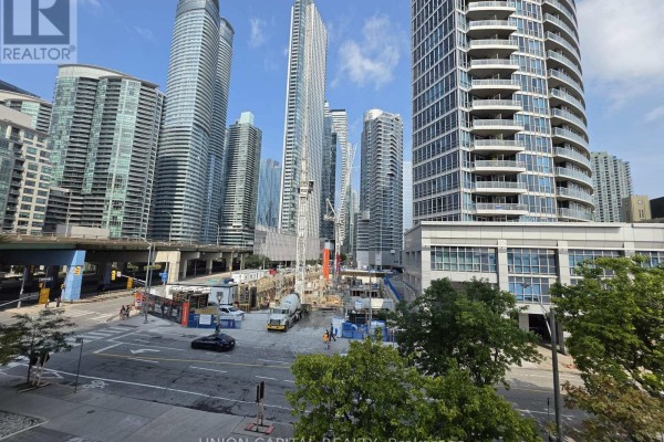 Living room with light wood floors, large windows, and city view. - 302 - 228 Queens Quay W, Toronto