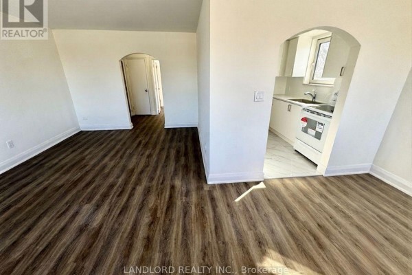 Living room with dark wood laminate flooring and an arched doorway to the kitchen. - 302 - 36 Wood Glen Road, Toronto