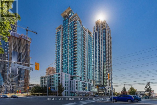 Exterior view of a modern high-rise condominium building on a sunny day with cranes nearby. - 302 - 3985 Grand Park Drive, Mississauga