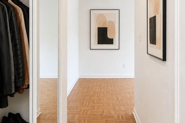 Hallway with wooden parquet flooring, modern art on the walls, and a closet with clothing. - 302 - 4 Sherbourne Street N, Toronto