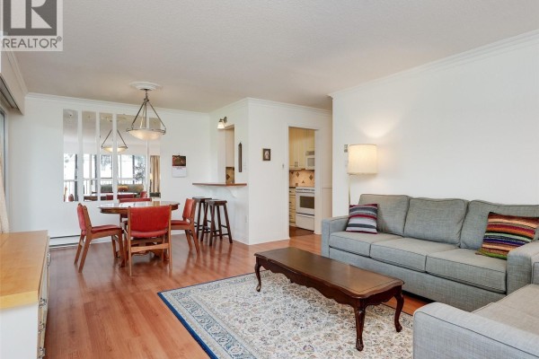 Living and dining area with wooden floors, sofa, coffee table, and dining set. - 302 1101 Hilda St, Victoria