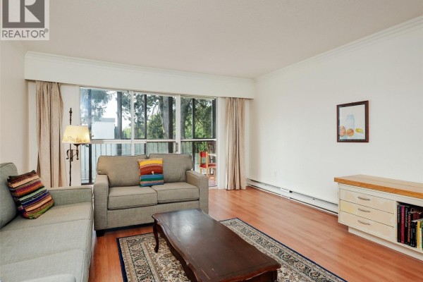 Living room with sofas, coffee table, rug, and view of balcony. - 302 1101 Hilda St, Victoria