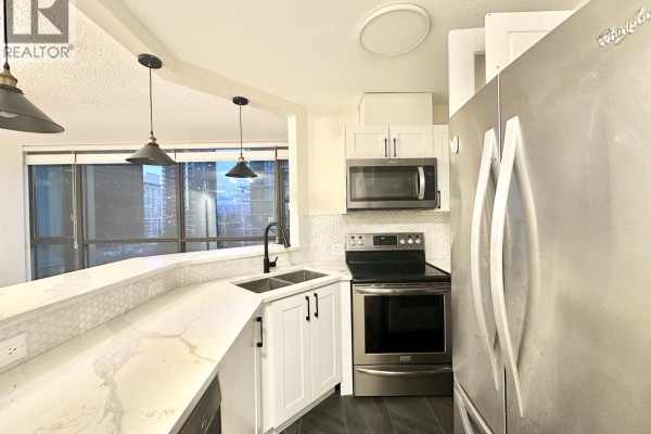 Modern kitchen with stainless steel appliances, white cabinets, and quartz countertops. - 302 1331 Alberni Street, Vancouver