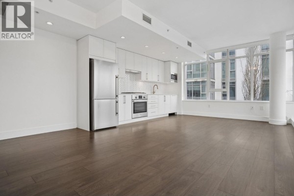 Spacious living area with hardwood flooring and large windows, showcasing city views. - 302 2455 Kingsway, Vancouver