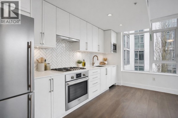 Close-up of kitchen featuring gas stove, white cabinets, and ample counter space. - 302 2455 Kingsway, Vancouver