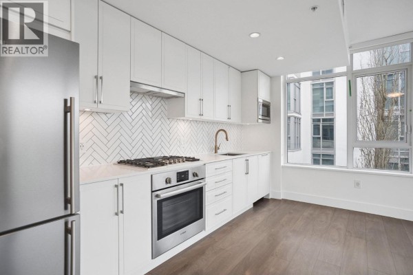 Detailed view of kitchen with stainless steel fridge, herringbone tile, and natural light from windows. - 302 2455 Kingsway, Vancouver