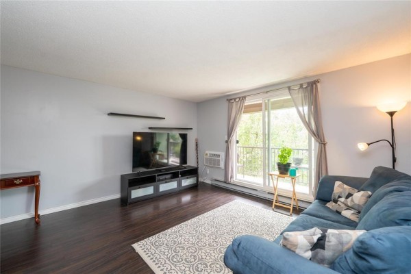 Aerial view of a brick apartment building and complex amenities including pool and pond. - 302 470 Kenaston Boulevard, Winnipeg