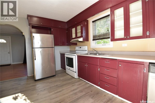 Kitchen with dark red cabinets, stainless steel refrigerator, and white appliances. - 302 Centre Street, Codette
