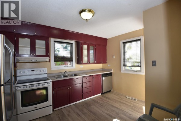 Kitchen featuring dark red cabinets, stainless steel dishwasher, and light yellow walls. - 302 Centre Street, Codette