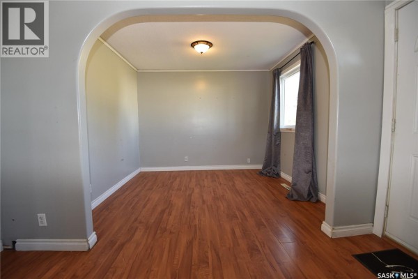 View through an arched doorway into a dining room with gray walls and wood flooring. - 302 Centre Street, Codette
