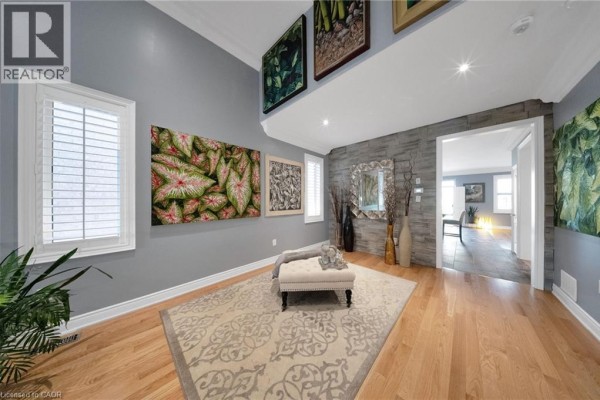 Living area with wood floors, a stone accent wall, plantation shutters, and a chaise lounge. - 302 Concession 3rd Road, Niagara On The Lake