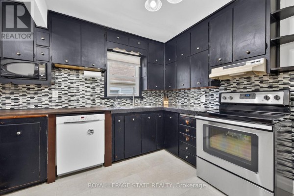A close-up view of a stainless steel double sink in a kitchen with dark cabinets. - 302 East 28th Street, Hamilton