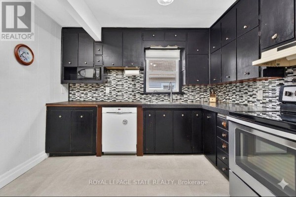 A stainless steel French door refrigerator stands in a kitchen with black cabinets and white walls. - 302 East 28th Street, Hamilton