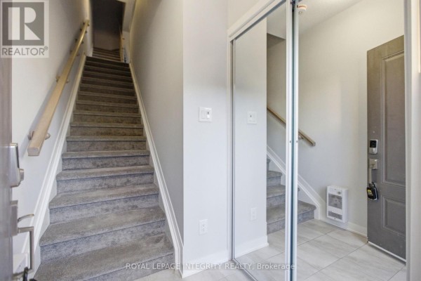 Empty bedroom with grey carpet and a window overlooking townhouses. - 302 Parnian Private, Ottawa
