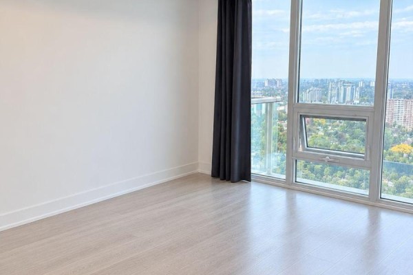 Apartment living area with large windows offering city views and light wood floors. - 3020 - 2031 Kennedy Road, Toronto