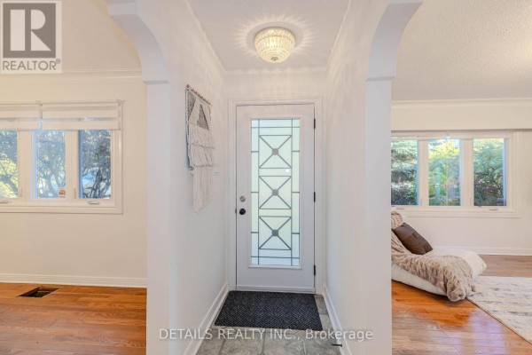 Entrance hallway with white walls, hardwood floors, and a glass-paned front door. - 3021 Richmond Road, Ottawa