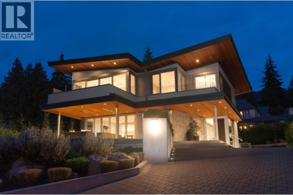 Contemporary home with cantilevered wood ceilings and large windows at dusk. - 3023 Mathers Avenue, West Vancouver