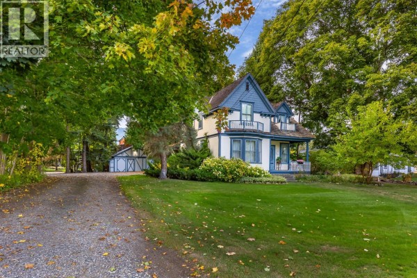 Gravel driveway leading to a white and blue house with mature trees. - 3025 Patterson Street, Armstrong