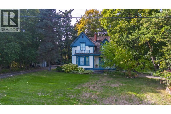 Exterior of a two-story white and blue house with a peaked roof, surrounded by trees. - 3025 Patterson Street, Armstrong