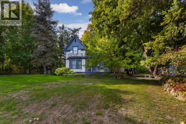Side view of a white and blue house with a porch, seen from a grassy yard. - 3025 Patterson Street, Armstrong
