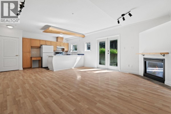 Living area with hardwood floors, fireplace, and view of kitchen and patio doors. - 3027 W 7th Avenue, Vancouver