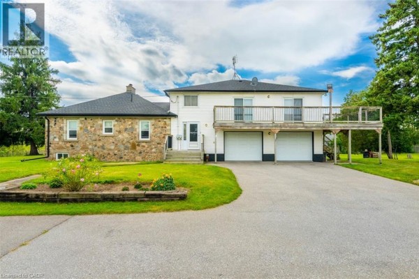 Front view of a stone and white house complex with two garage doors and a raised balcony off the white section. - 3029 Burnhamthorpe Road W, Milton
