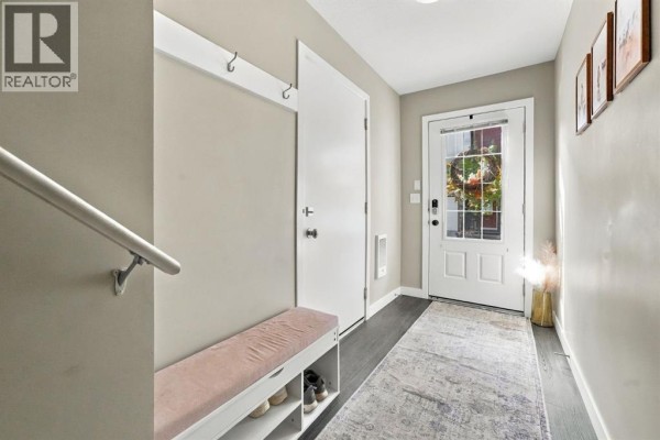 Entrance hallway with a beige bench, shoe storage, white door, and front door with glass. - 303, 125 Caribou Crescent, Red Deer