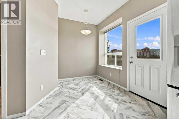 Open concept living and kitchen area with light wood laminate flooring, neutral walls, and a wooden kitchen island with stools. - 303, 2005 Luxstone Boulevard Sw, Airdrie