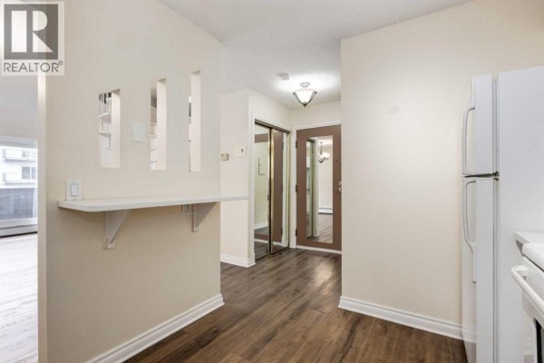 Kitchen area with a breakfast bar, pass-through, and view of the entryway. - 303, 730 2 Avenue Nw, Calgary