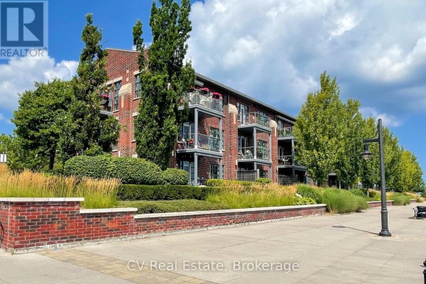 Side view of the brick apartment building with balconies, manicured bushes, and trees. - 303 - 1 Shipyard Lane, Collingwood