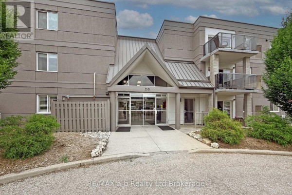 Front entrance of apartment building with glass doors and stone accents. - 303 - 159 Ferguson Drive, Woodstock