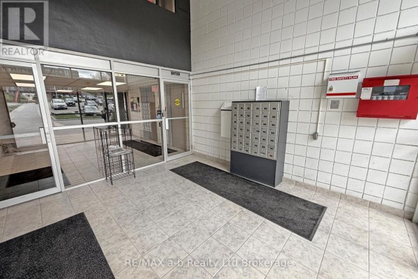 Apartment building lobby with mailboxes, tile walls, and glass doors. - 303 - 159 Ferguson Drive, Woodstock