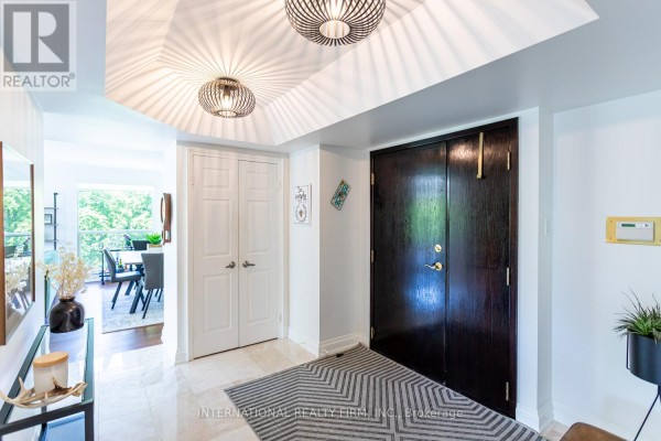 Foyer with dark wood double doors, white double doors, and a view of a dining area. - 303 - 1700 The Collegeway, Mississauga