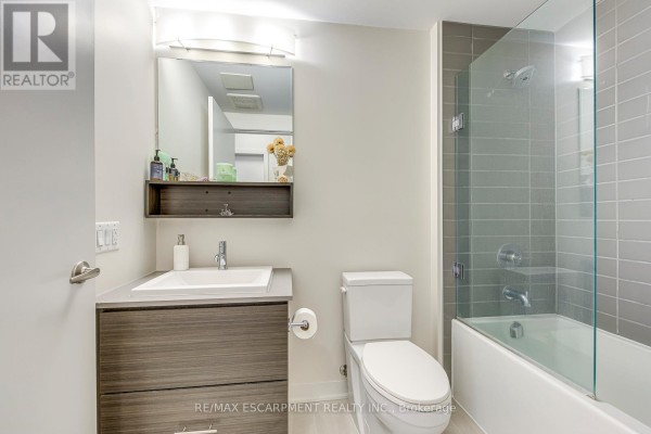 Modern bathroom vanity, toilet, and bathtub with glass shower door - 303 - 320 Plains Road E Burlington