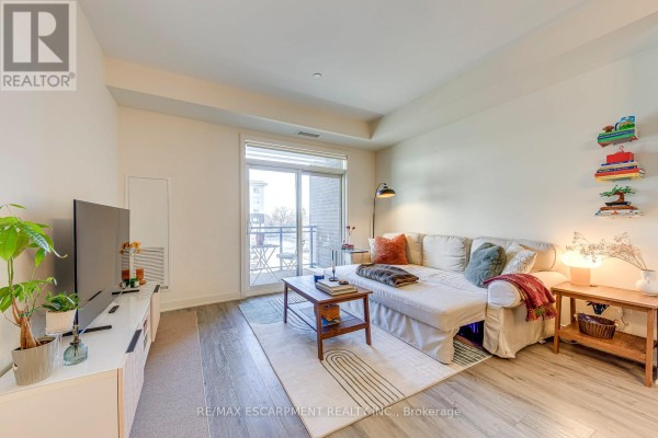 Living room with sofa, TV, coffee table & balcony - 303 - 320 Plains Road E Burlington